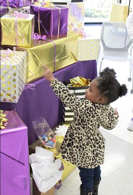 孩子拿着紫色和金色包装的礼物